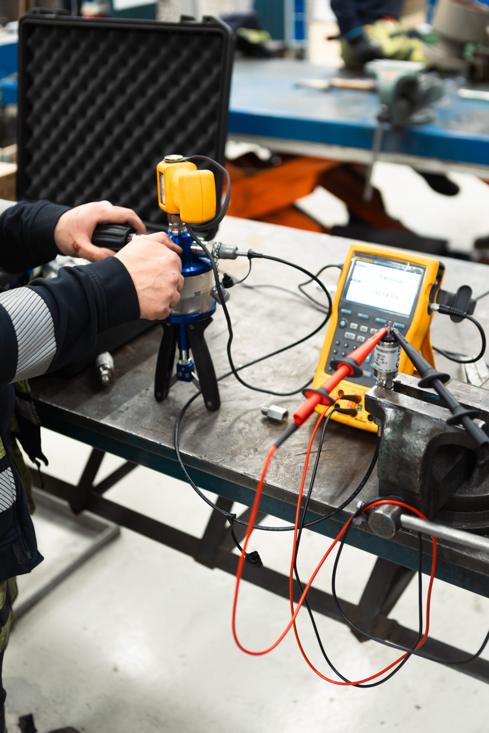 Ventiltekniker utför funktionskontroll med gul mätinstrument och sensor på ventilkomponent i verkstad