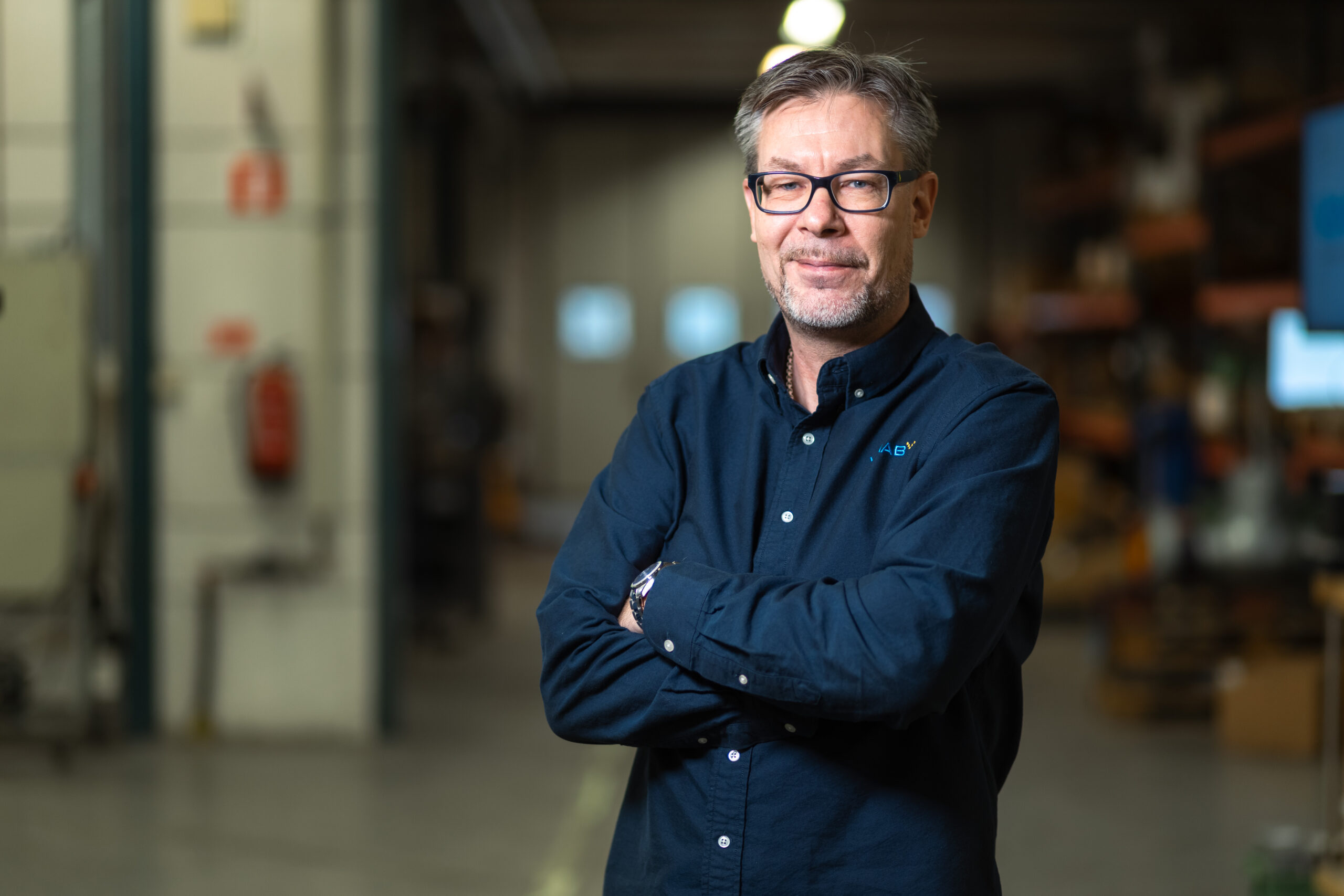 Medarbetare på VIMAB med korslagda armar i industriell verkstadsmiljö för ventilservice