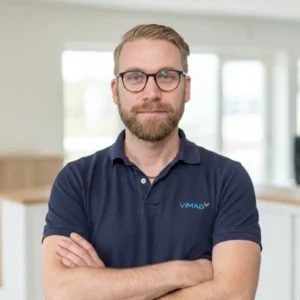 VIMAB-medarbetare med korslagda armar i marinblå pikétröja med VIMAB-logotyp