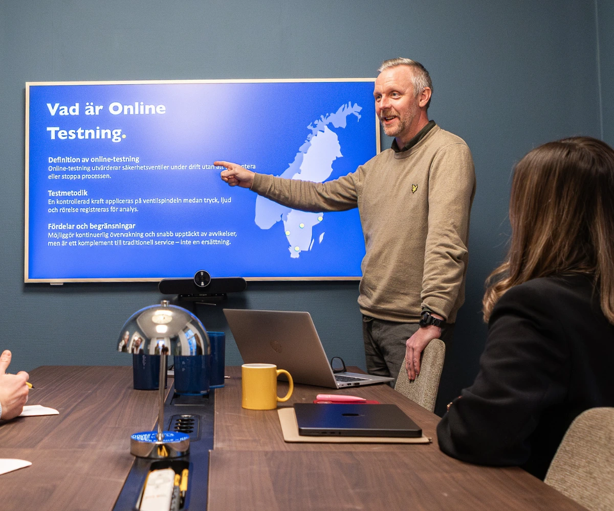 VIMAB-tekniker presenterar online-testning av ventiler för deltagare vid konferensbord med laptop och skärm