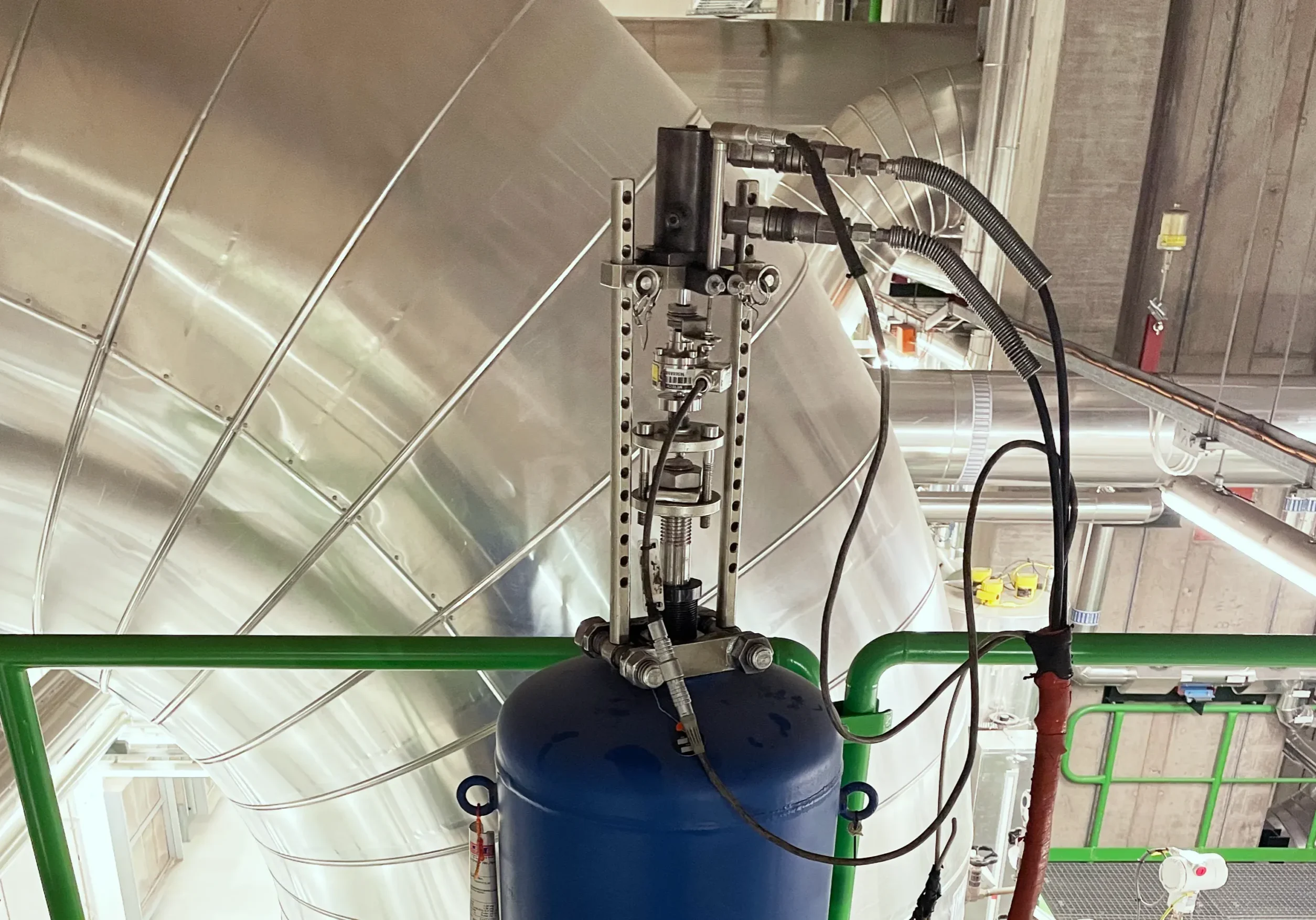 Säkerhetsventil med aktuator och hydrauliska slangar monterad på blå tryckkärl vid stor rörledning i processindustri