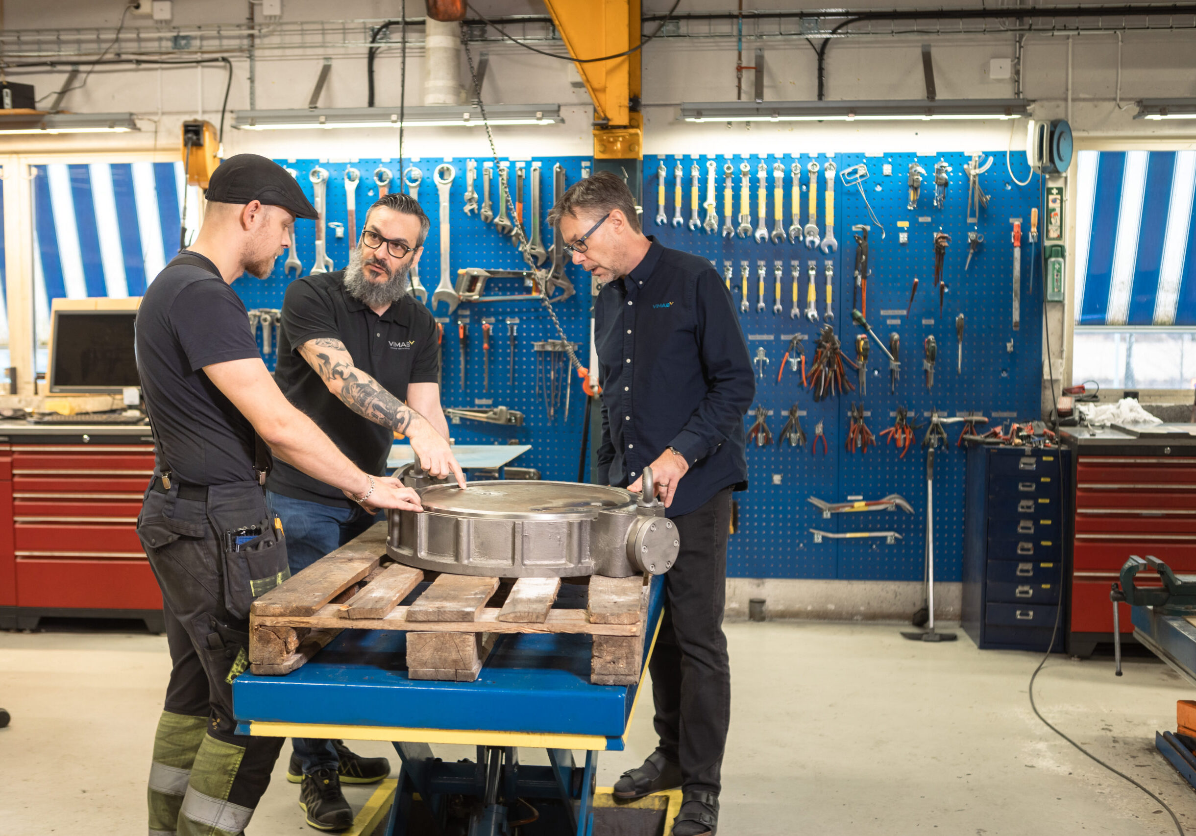 Tre ventiltekniker på VIMAB samarbetar kring renovering av stor industriventil i modern verkstad